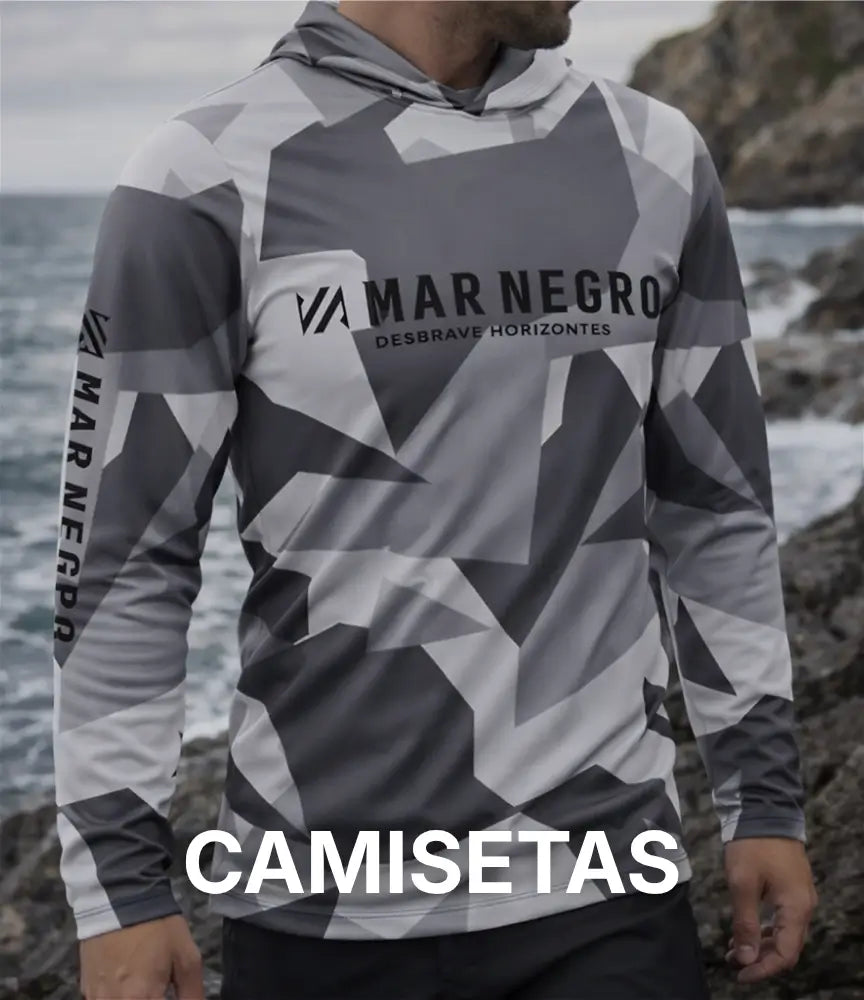 Um pescador usando uma camisa de pesca da Mar Negro, ele está na costeira rochosa de uma praia