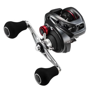 A Carretilha Shimano Scorpion vista na diagonal direita, com sua manivela alongada e seus pegadores emborrachados em foco, ao fundo tem seu ajuste fino e seu guia de linha