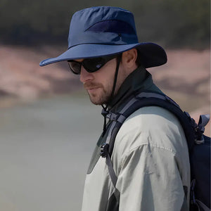 Chapéu de Pesca Zanter Air Field azul-escuro usado por pescador de perfil com mochila e óculos escuro