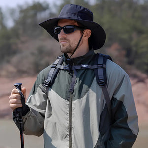 Chapéu de Pesca Zanter Air Field preto usado por um pescador com mochila e bastão, o chapéu apresenta sua aba larga e seu cordão de ajuste no queixo