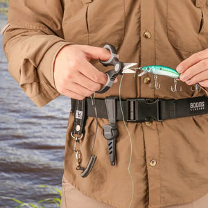 Pescador segurando uma isca artificial presa à uma linha, e com a outra mão a Tesoura de Pesca Booms Cut Pro corta a linha