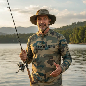 Pescador com um chapéu visto de frente segurando uma vara de pesca, usando a Camisa de Pesca Mar Negro Sublimada Capuz Caqui