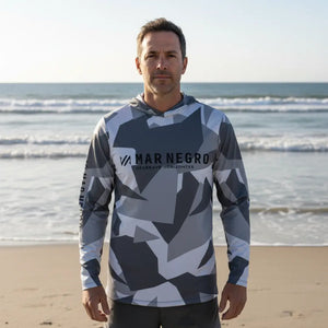 Um pescador visto de frente as margens de uma praia com os braços esticados, usando a Camisa de Pesca Mar Negro Sublimada Capuz Geométrica