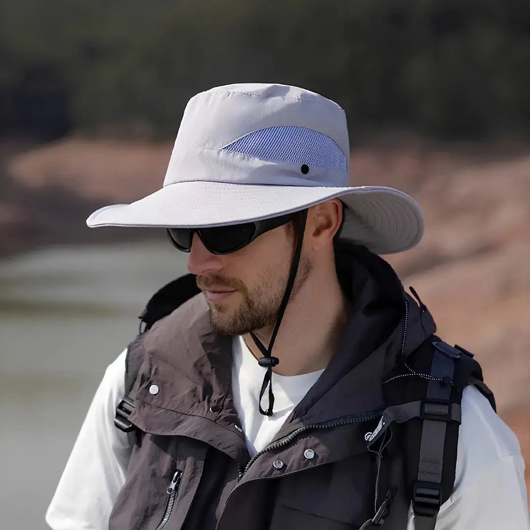 Chapéu de Pesca Zanter Air Field cinza-claro usado um pescador, com destaque para seu cordão de ajuste, sua tela em mesh e sua aba larga