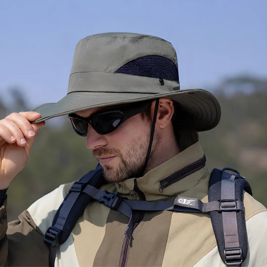 Pescador mostrado de lado e usando o Chapéu de Pesca Zanter Air Field verde-militar, ele está segurando a aba do chapéu, também é possível ver sua tela respirável na cor preta