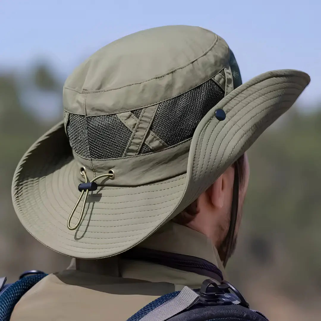 Um pescador mostrado de costas, ele está usando o Chapéu de Pesca Zanter Hunter na cor verde, é possível ver sua tela em mesh e seu ajuste de cabeça