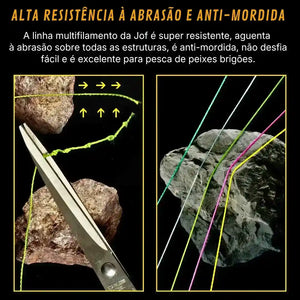 Linha multifilamento Jof Power 4x sendo cortada por uma tesoura e com duas pedras ao fundo do lado esquerdo, e do lado direito 5 fios em cores variadas em cima de uma pedra