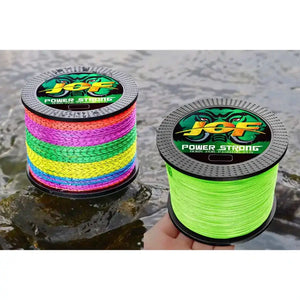 Dois carretéis da linha multifilamento Jof Power 4x nas cores multicoloridas e verde em cima de uma pedra na beira do mar