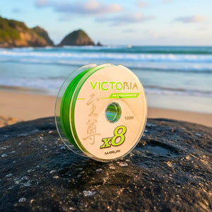 Carretel da Linha Multifilamento Maruri Victoria 8x na cor verde em cima de uma pedra molhada, na beira de uma praia